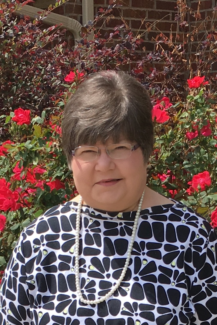 Diane Lopp standing in front of red roses