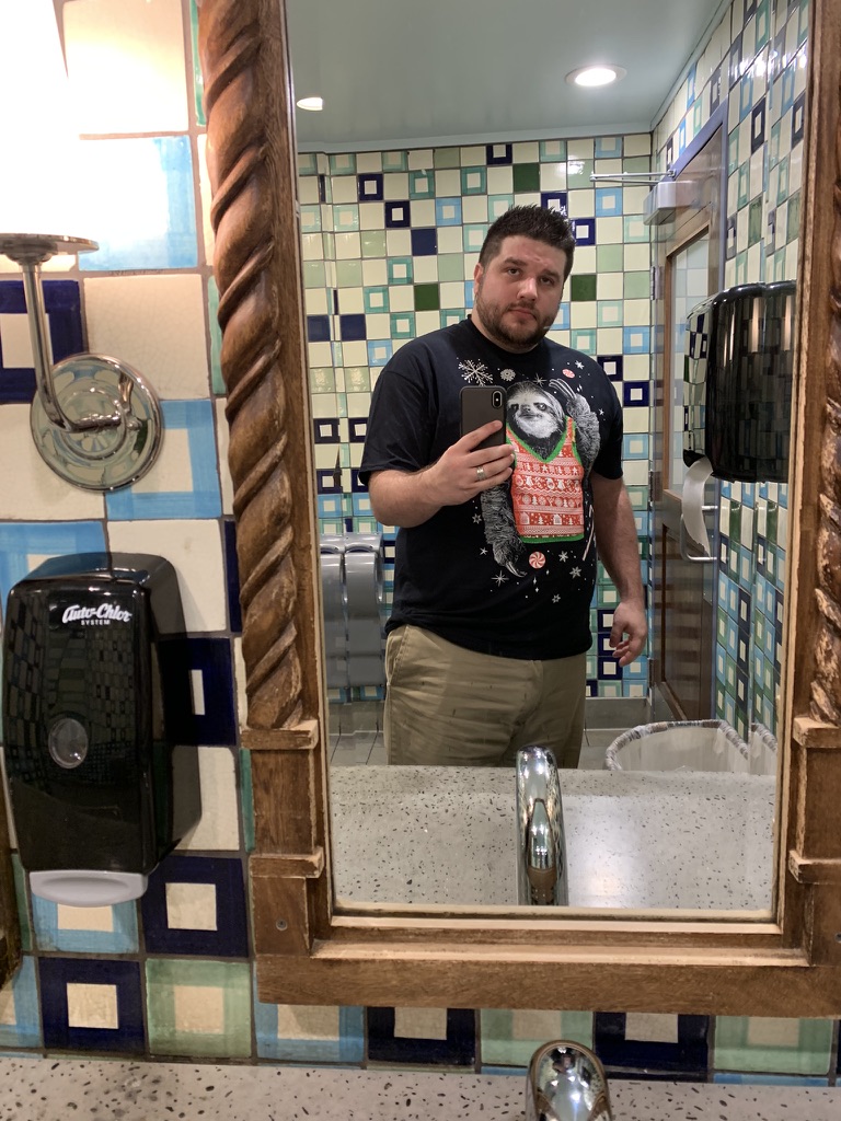 Shawn Lopp taking an iPhone mirror photo in a tiled bathroom