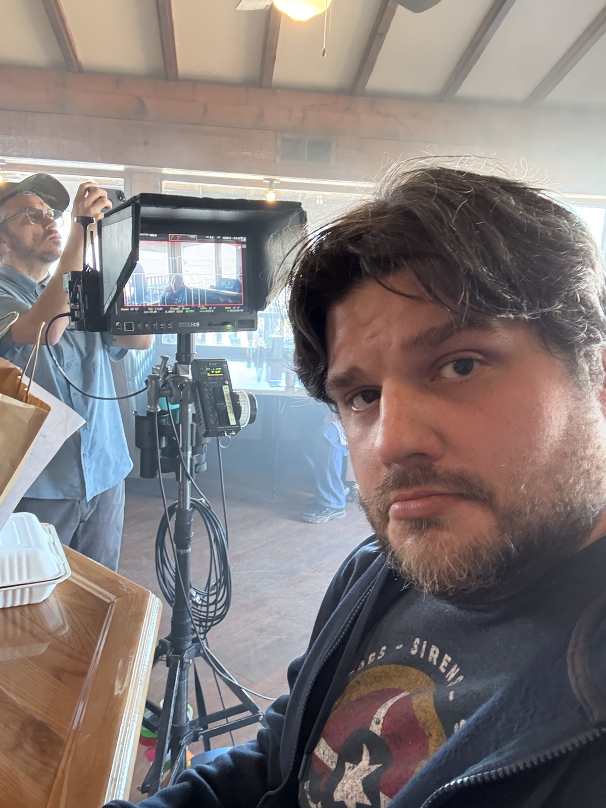 Shawn Lopp beside a production camera and monitor on the set of The Lowdown