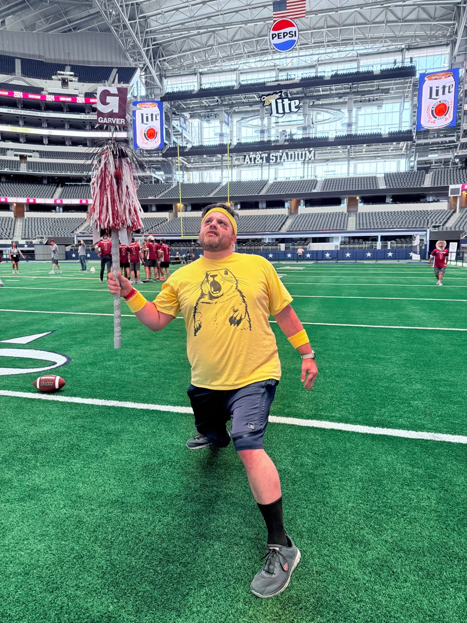 Shawn Lopp on a football field holding a mascot prop